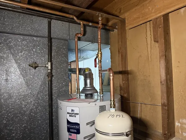 Copper piping and expansion tank on a 50-gallon water heater installed by Poor John's Plumbing in Kansas City